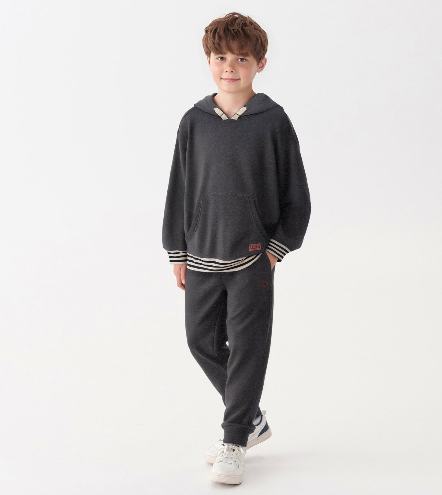 Charcoal melange pullover hoodie with a front pocket and striped hem, worn by a boy with casual pants and sneakers.