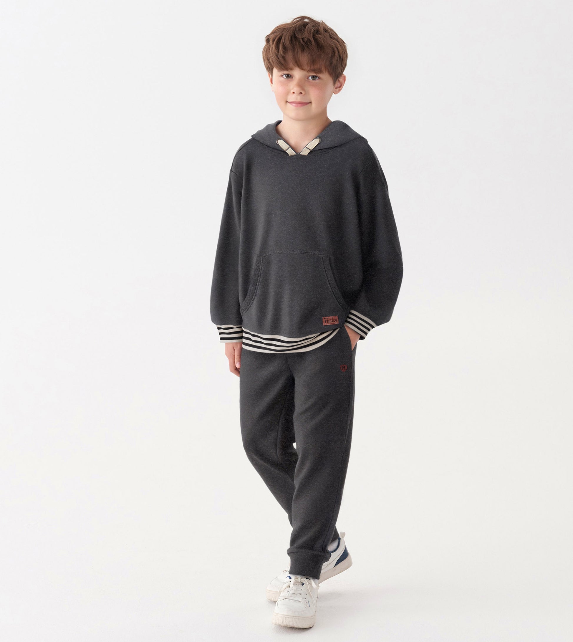 Charcoal melange pullover hoodie with a front pocket and striped hem, worn by a boy with casual pants and sneakers.