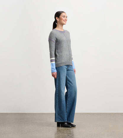 Charcoal melange sweater with colorful striped sleeves, paired with wide-leg jeans and heeled boots, shown from the side.