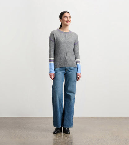 Charcoal melange sweater with colorful striped sleeves, round neckline, and a relaxed fit, worn with wide-leg jeans.