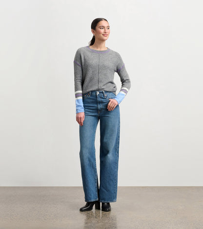 Charcoal melange sweater with contrasting blue and purple striped sleeves, styled with high-waisted jeans.