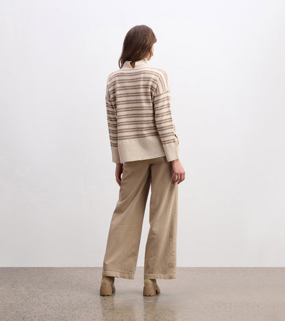 Mock neck sweater in camel with double stripes, featuring a relaxed fit and ribbed hem, styled with beige wide-leg pants.