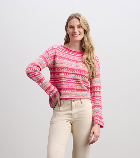 Colorful pink sweater with a striped pattern, featuring long sleeves and a relaxed fit, paired with light-colored pants.