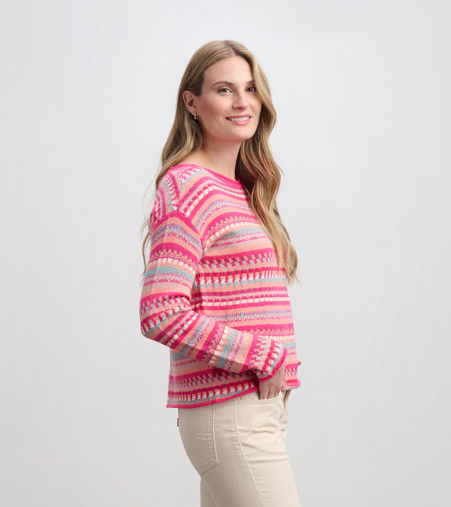 Colorful striped sweater in pink, blue, and cream, featuring a relaxed fit and long sleeves, styled with light pants.