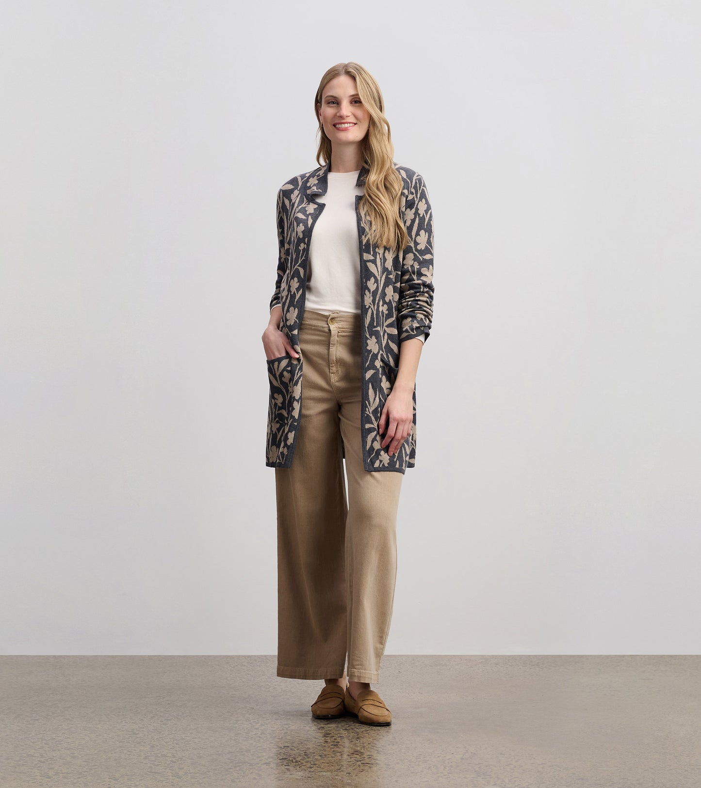Long-sleeve sweater blazer featuring a floral vine pattern in navy and cream, styled with wide-leg beige pants.