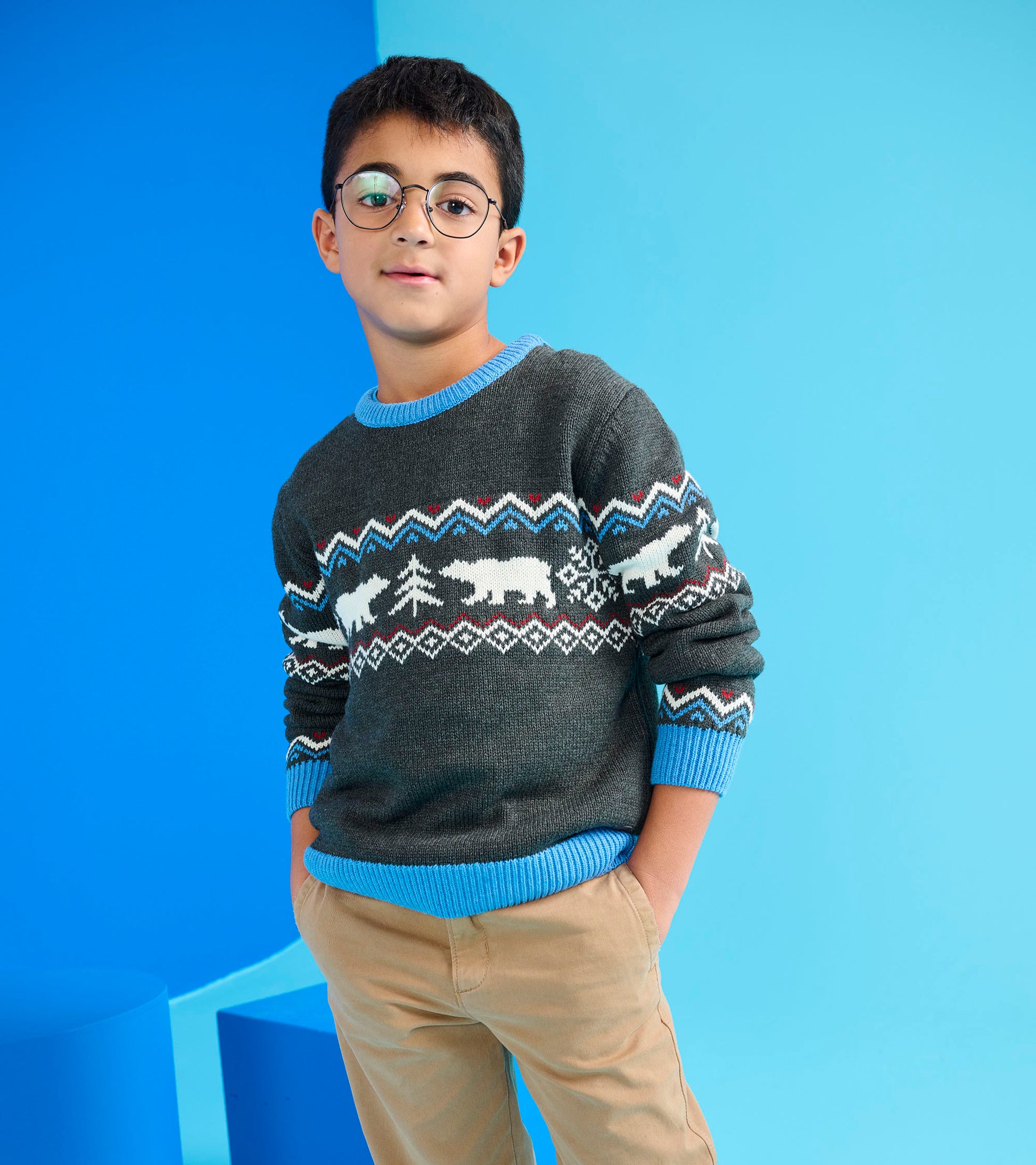 Gray crew neck sweater featuring a winter-themed pattern with polar bears and trees, paired with beige pants.