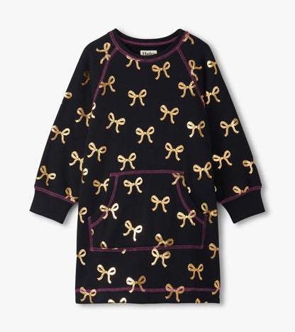 Black sweater dress featuring gold bow patterns and a front pocket, with purple stitching accents. Suitable for girls.