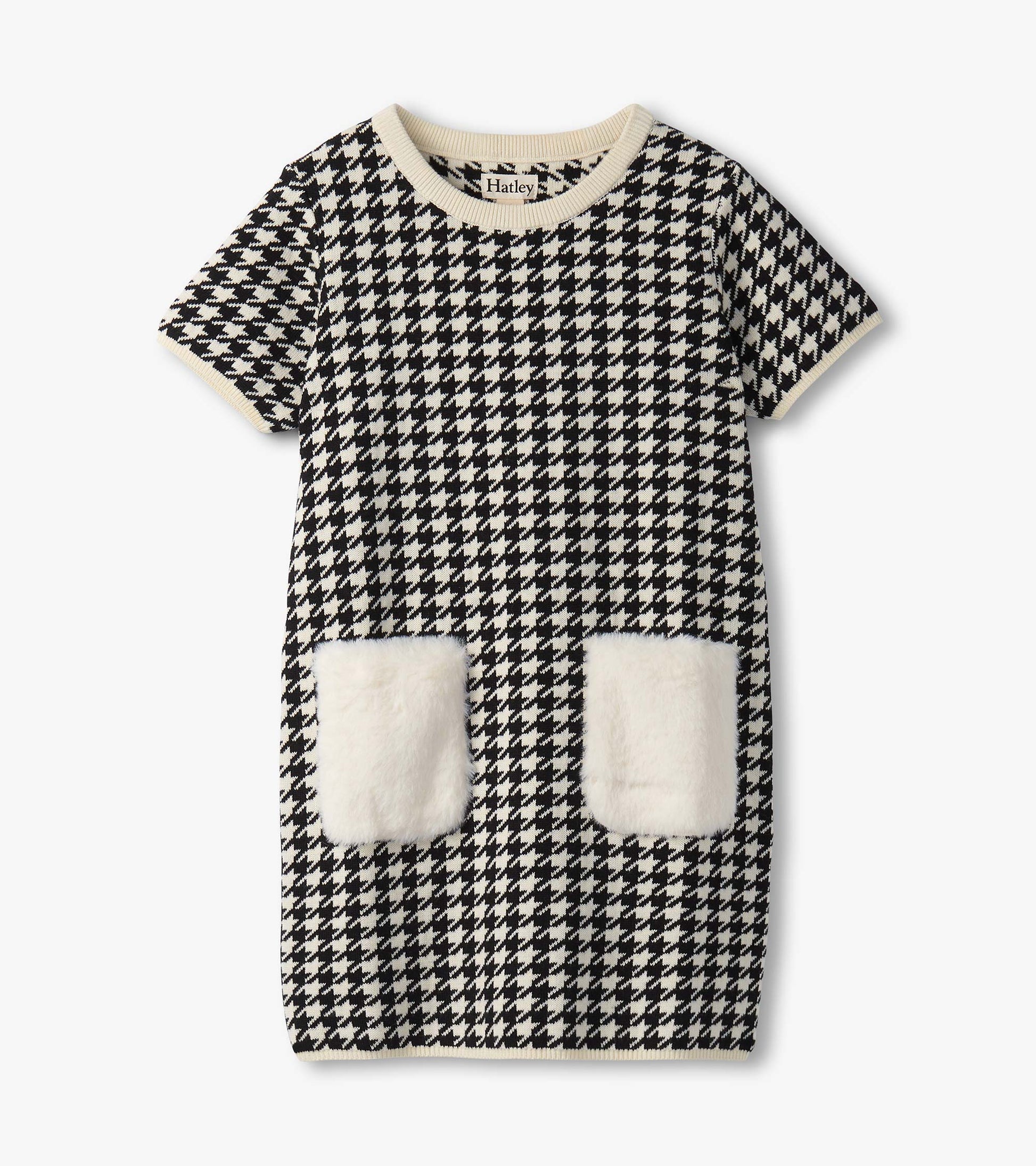 Black and white houndstooth sweater dress featuring faux fur pockets and a ribbed neckline. Short sleeves, knee-length desig…