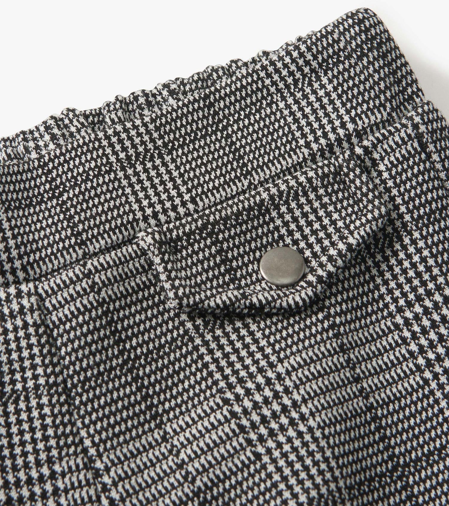 Black and white houndstooth plaid wide leg pants with an elastic waistband and a decorative button detail.