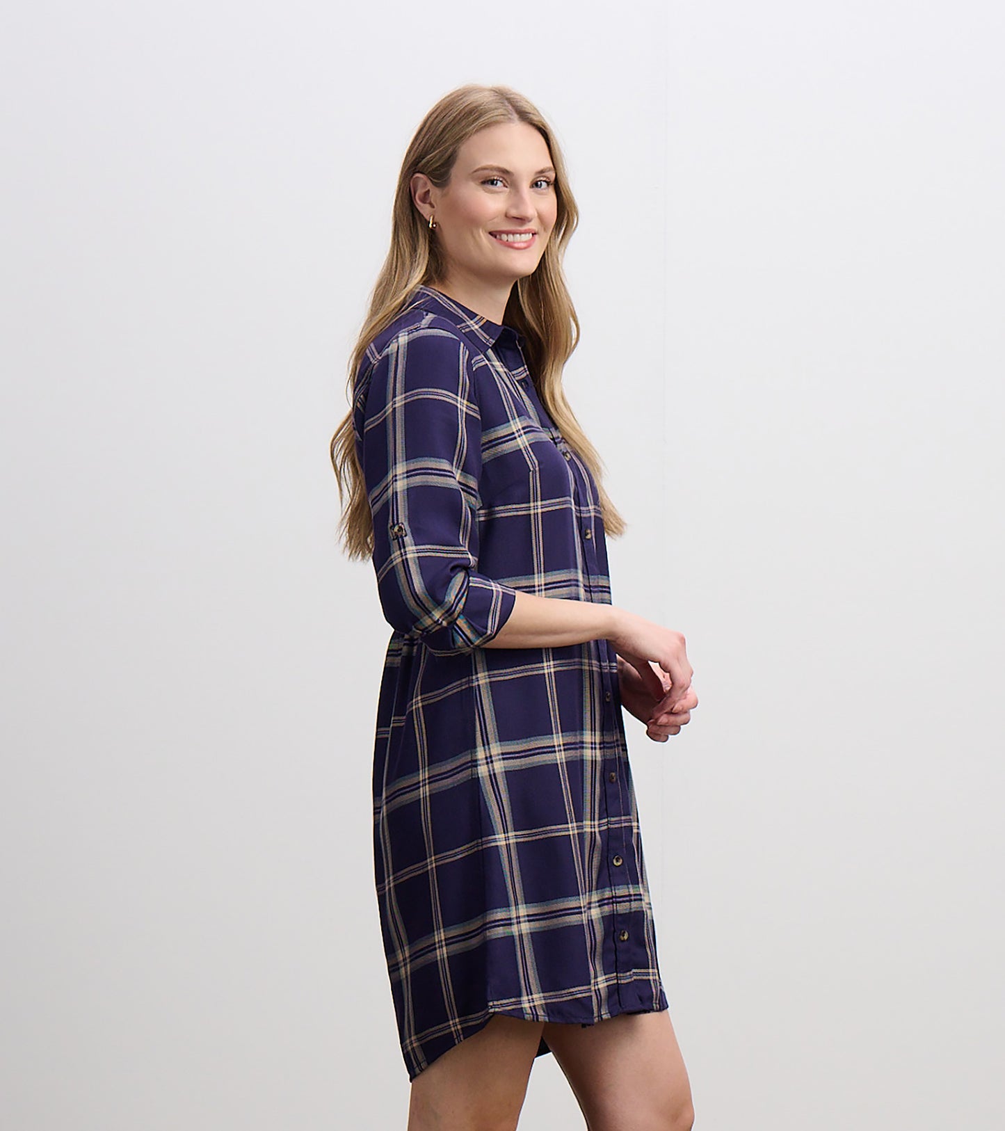 Side view of navy plaid shirt dress with collar, button front, rolled sleeves, and curved hem