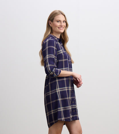 Side view of navy plaid shirt dress with collar, button front, rolled sleeves, and curved hem