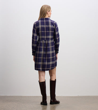 Back view of navy plaid shirt dress with long sleeves, gathered waist seam, and curved hem