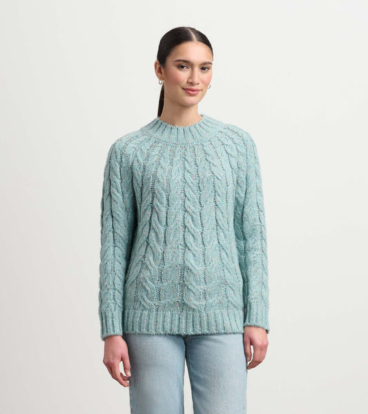 Light turquoise cable knit sweater with a round neckline and long sleeves, styled with light denim jeans.