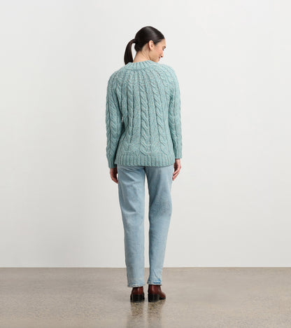 Light turquoise cable knit sweater with a relaxed fit, featuring a round neckline and long sleeves, viewed from the back.