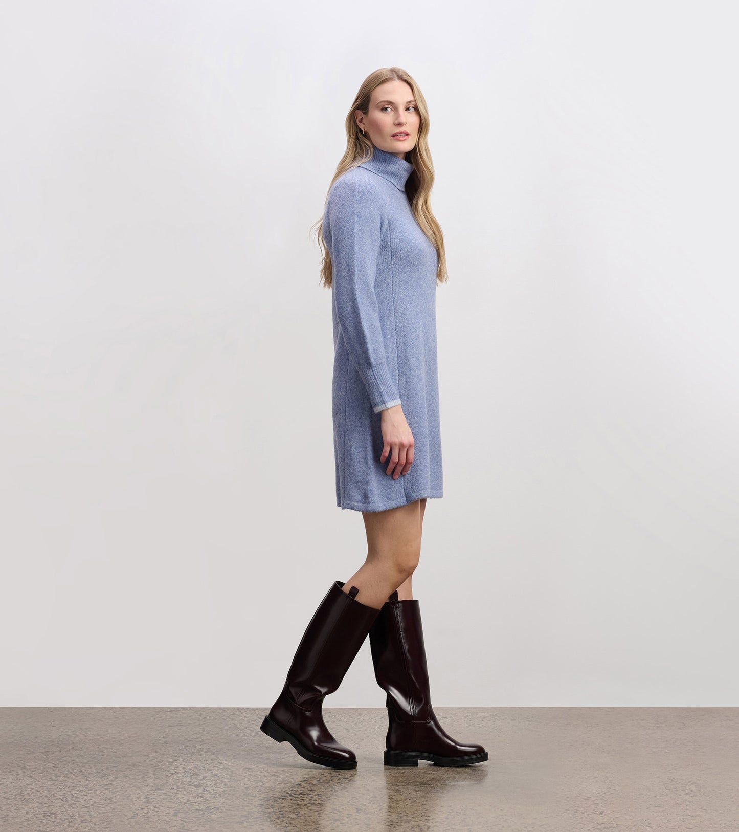 Light denim sweater dress with a high collar, long sleeves, and a relaxed fit, paired with knee-high brown boots.