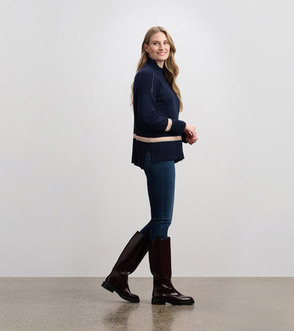 Navy mock neck sweater with light pink stripes, featuring a relaxed fit and side slits, styled with jeans and knee-high boot…