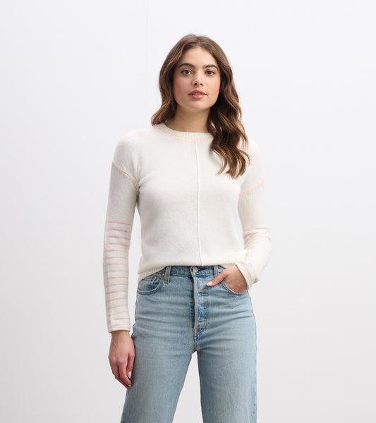 Cream sweater with striped sleeves and a round neckline, styled with light blue jeans.
