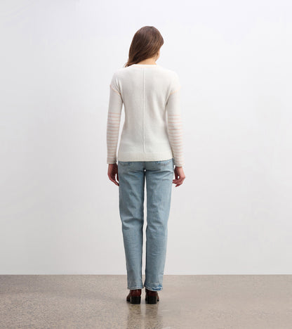 Cream sweater with striped sleeves, fitted shape, and ribbed hem, worn with light blue jeans, viewed from the back.