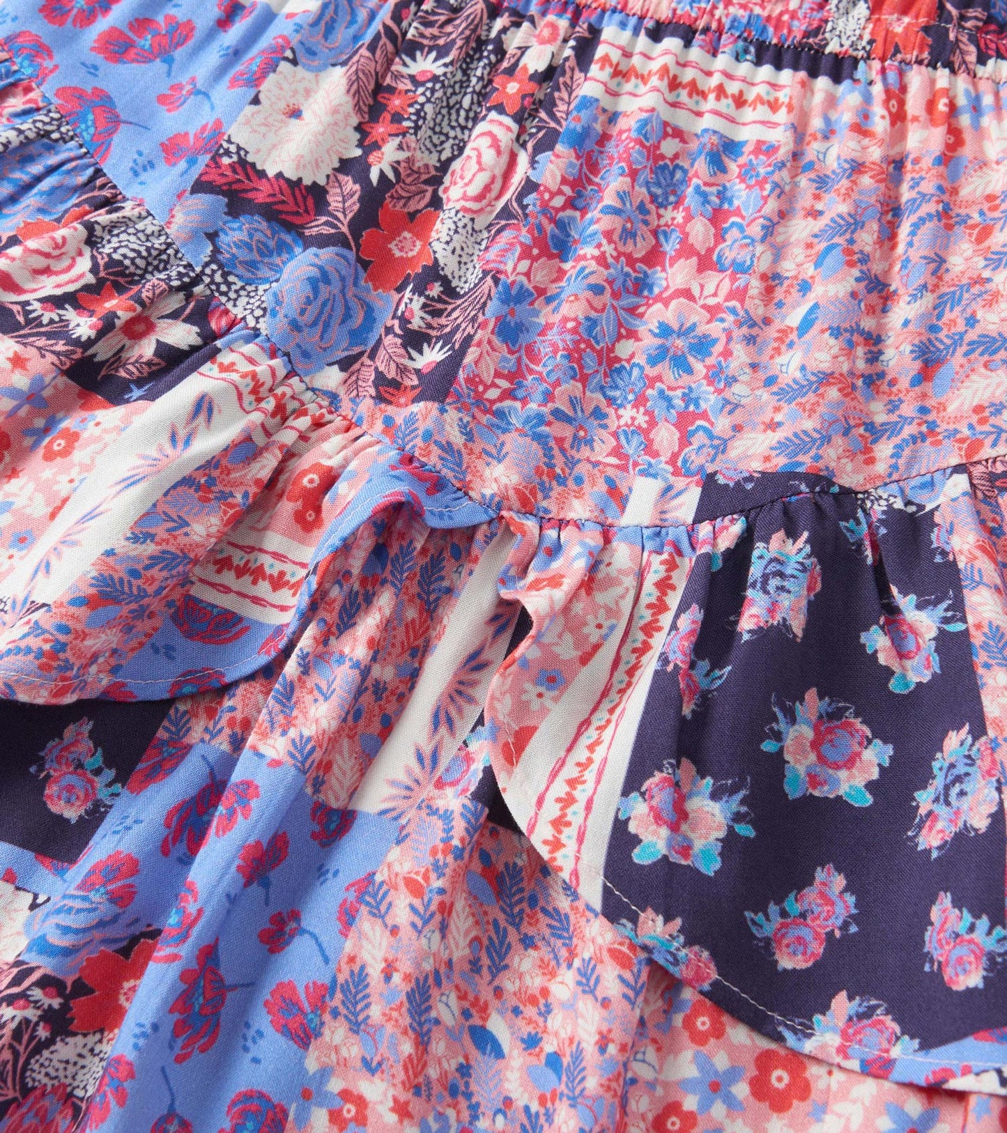Colorful patchwork floral dress featuring ruffled flounce details in shades of pink, blue, and navy.