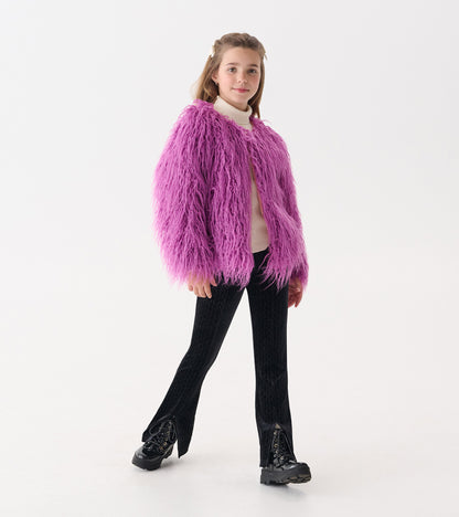 Radiant orchid faux fur topper with long sleeves, worn over a light sweater and paired with black pants and boots.