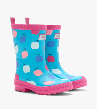 Pair of blue kids rain boots with pink trim and multicolor apple print, front three-quarter view