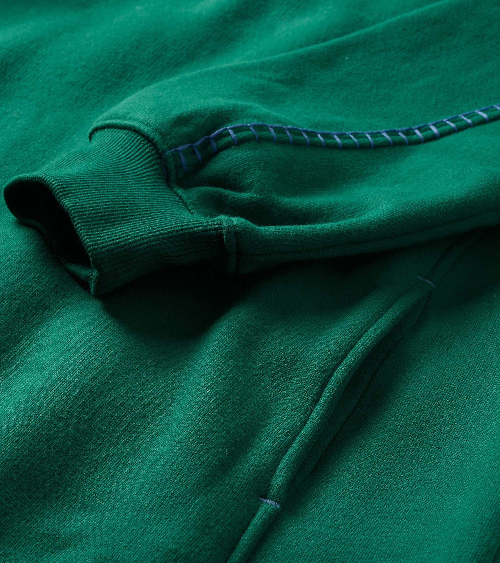 Close-up of the green dress showing ribbed cuff, pocket seam, and contrast stitching detail