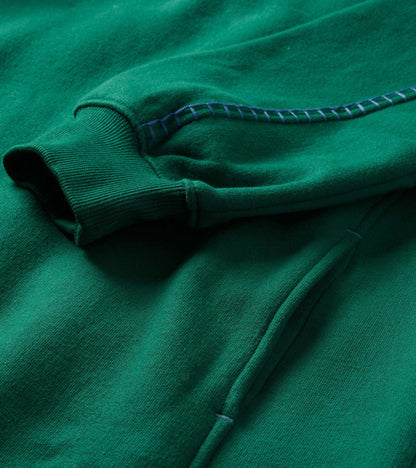 Close-up of the green dress showing ribbed cuff, pocket seam, and contrast stitching detail