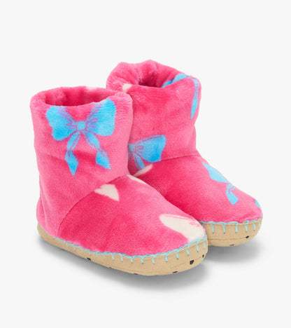 Pair of pink slipper boots with blue bow print and tan soles, shown from the front at an angle