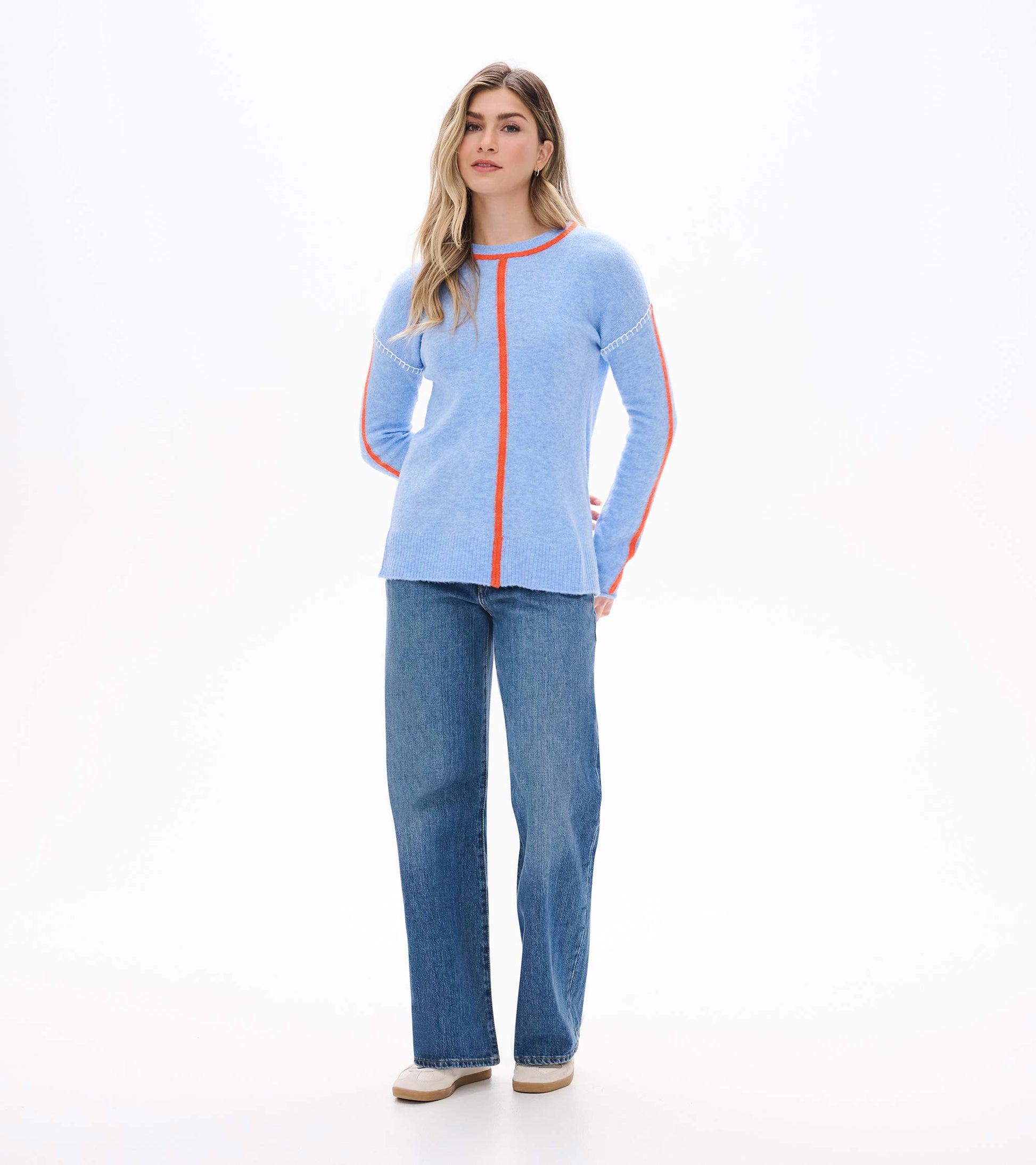 Full front view of azure blue Maeve sweater with orange contrast trim, worn with wide-leg jeans