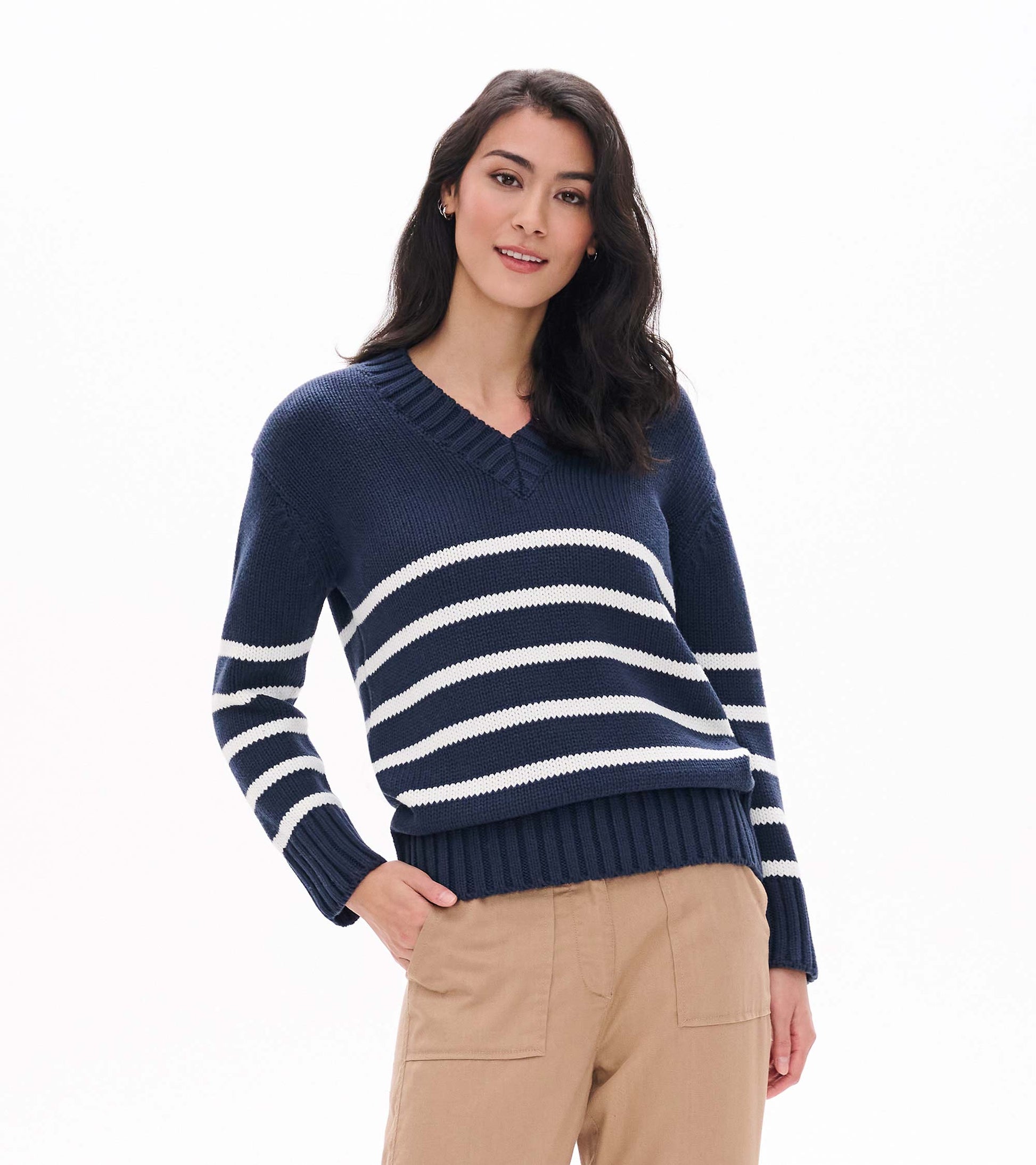 Front view of navy V-neck sweater with cream stripes and ribbed cuffs and hem on model