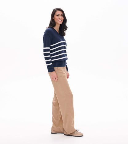 Side view of navy V-neck sweater with cream stripes and ribbed hem on model