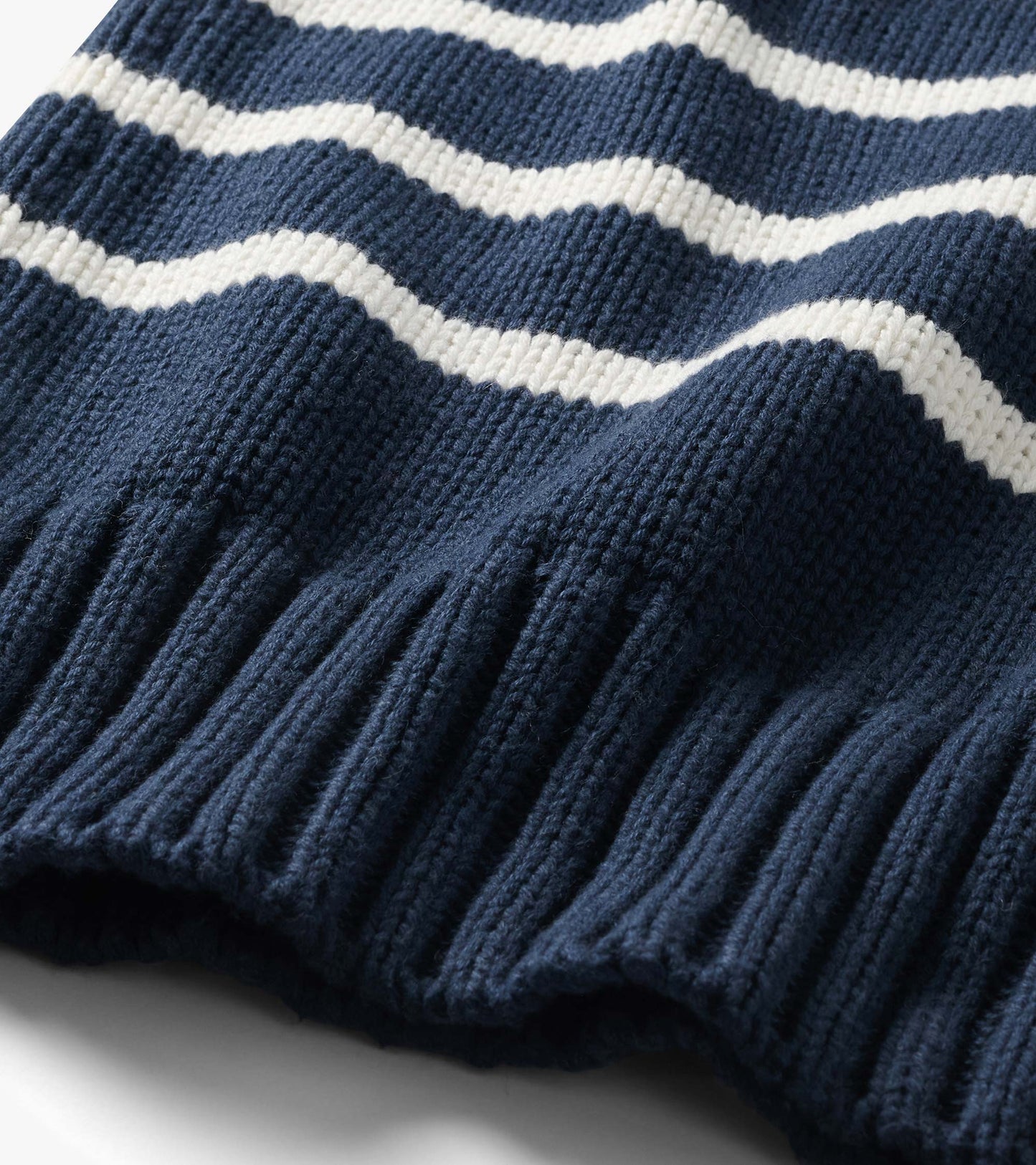 Close-up of the navy sweater with cream stripes and wide ribbed hem detail