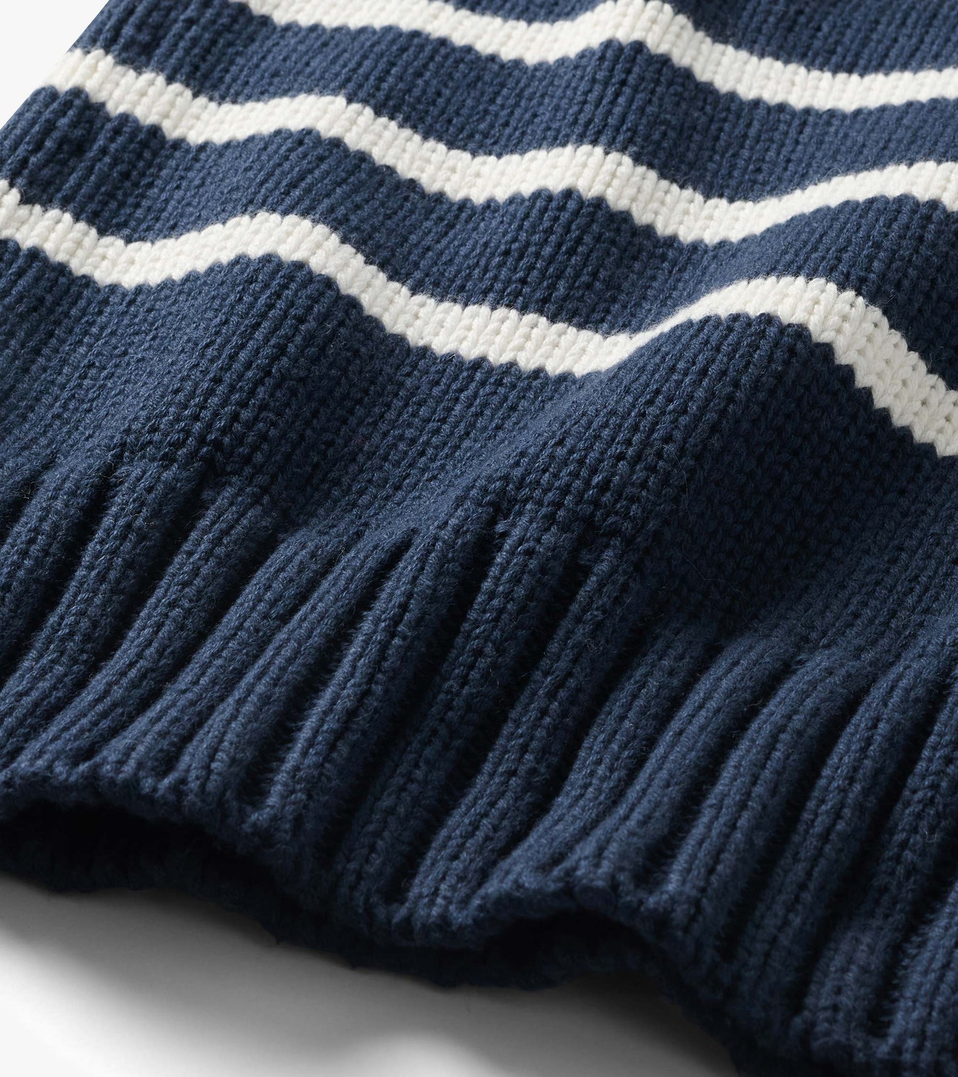 Close-up of the navy sweater with cream stripes and wide ribbed hem detail