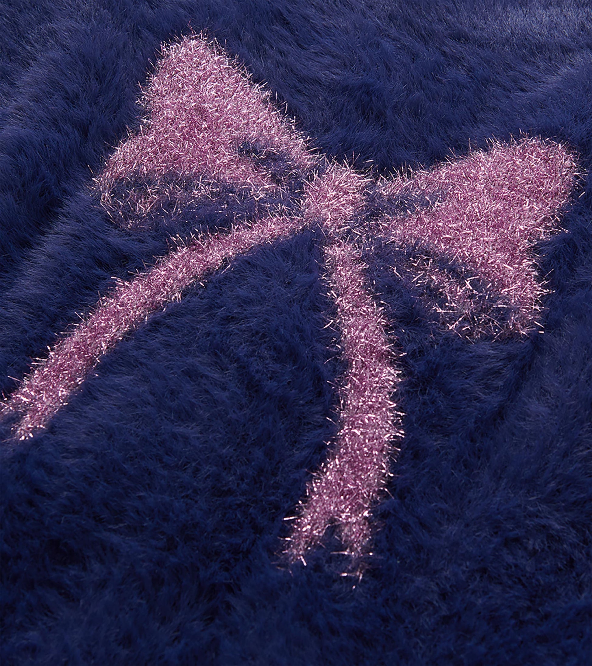 Close-up of pink bow detail on deep blue fuzzy cardigan
