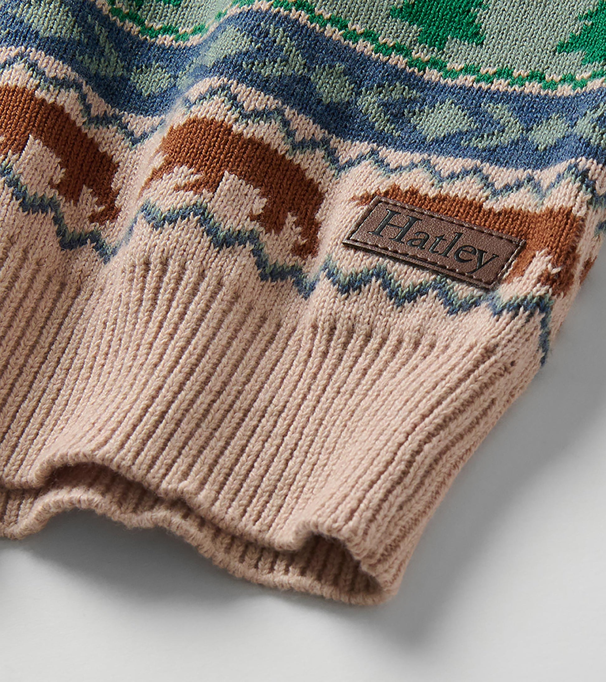 Close-up of sweater hem with ribbed trim, bear pattern, and visible Hatley logo patch