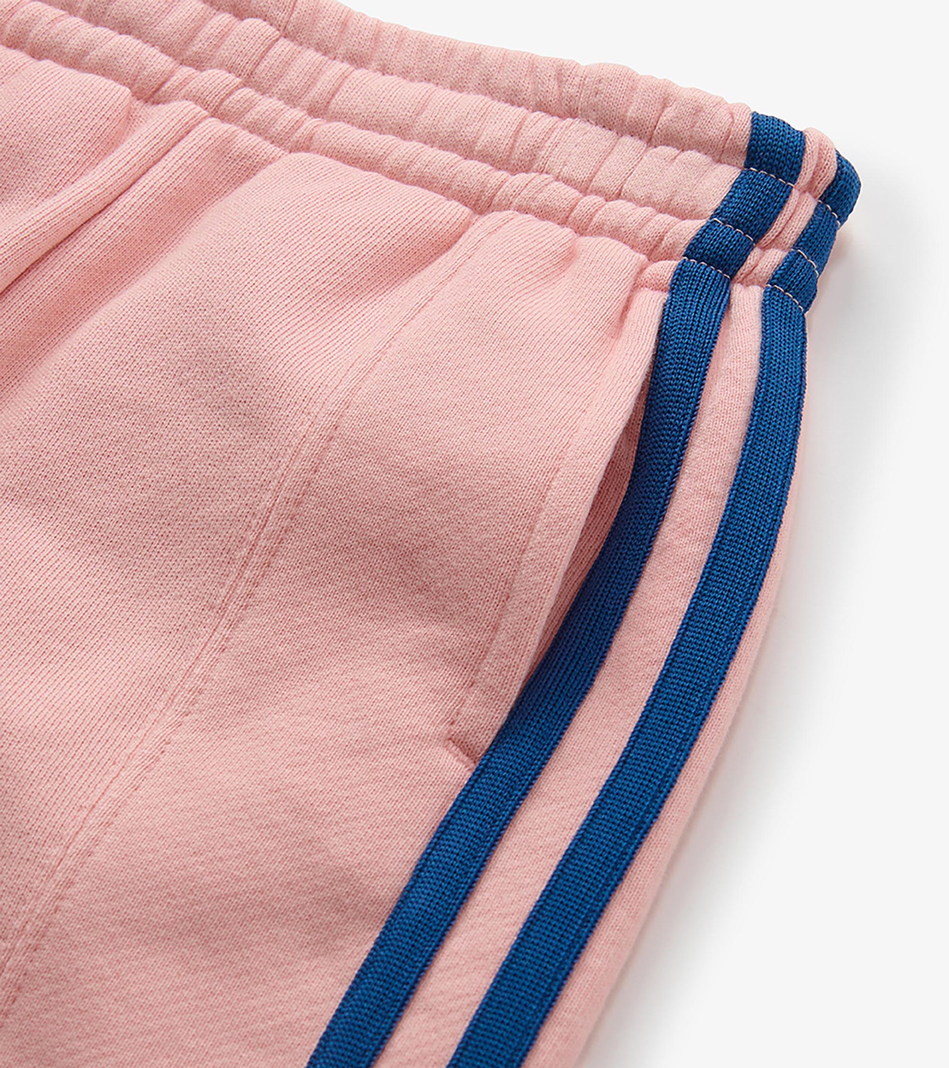 Close-up of pink track pants waistband and pocket with blue side stripes