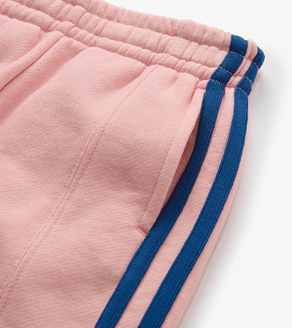 Close-up of pink track pants waistband and pocket with blue side stripes