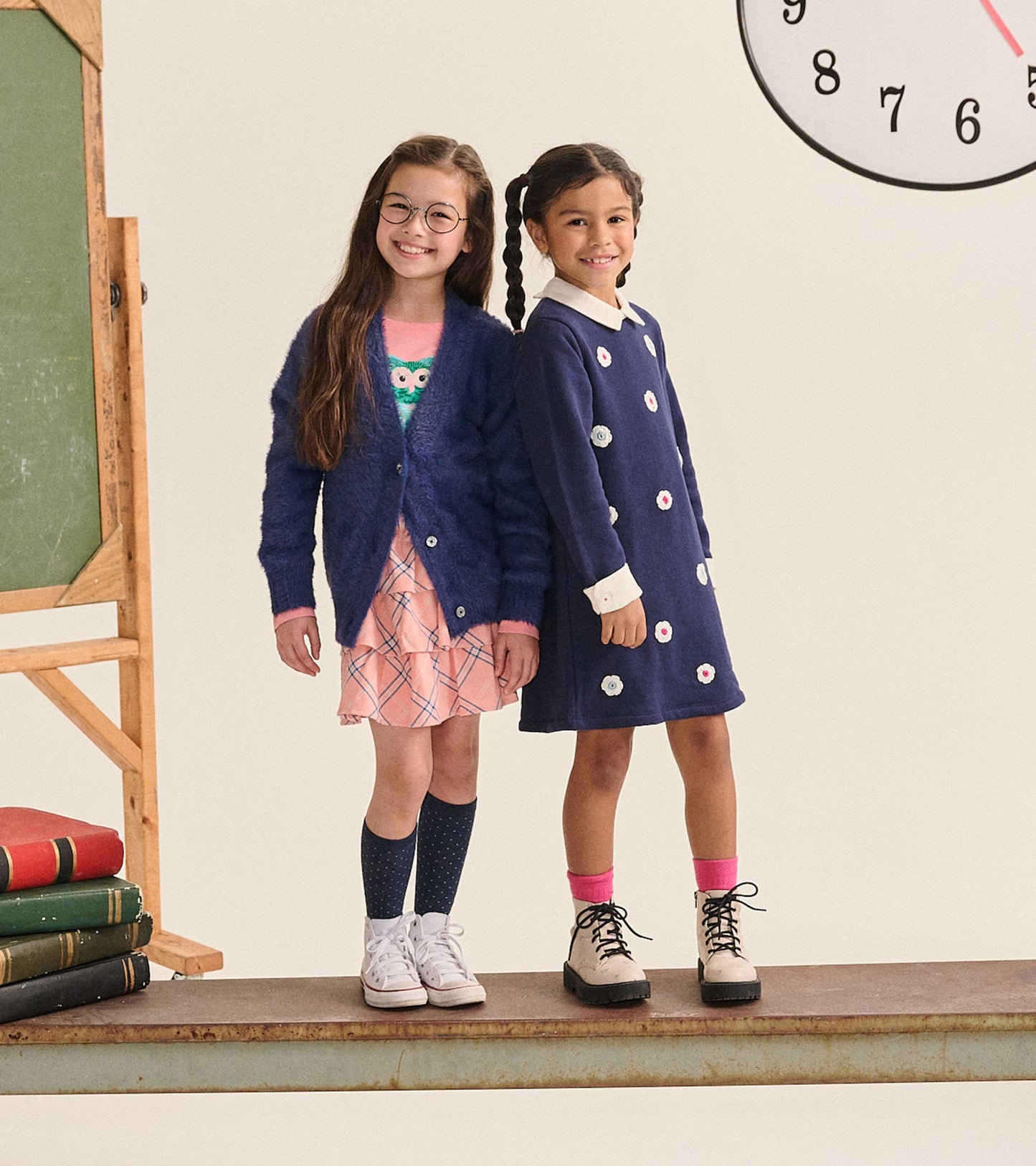 Girl wearing a pink plaid ruffle skirt with a navy cardigan in a classroom setting
