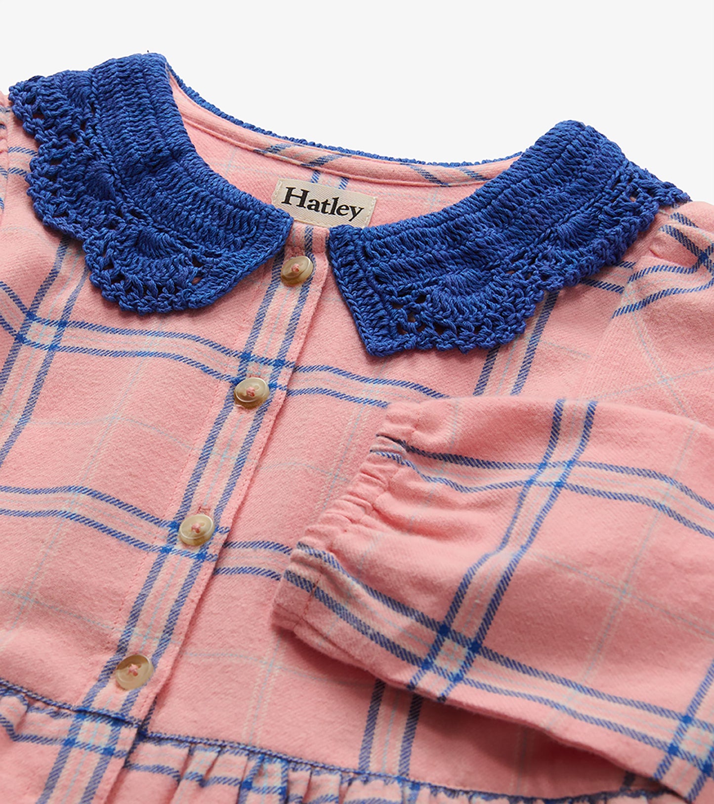 Close-up of pink plaid dress with blue crochet Peter Pan collar, front buttons, and elastic cuff