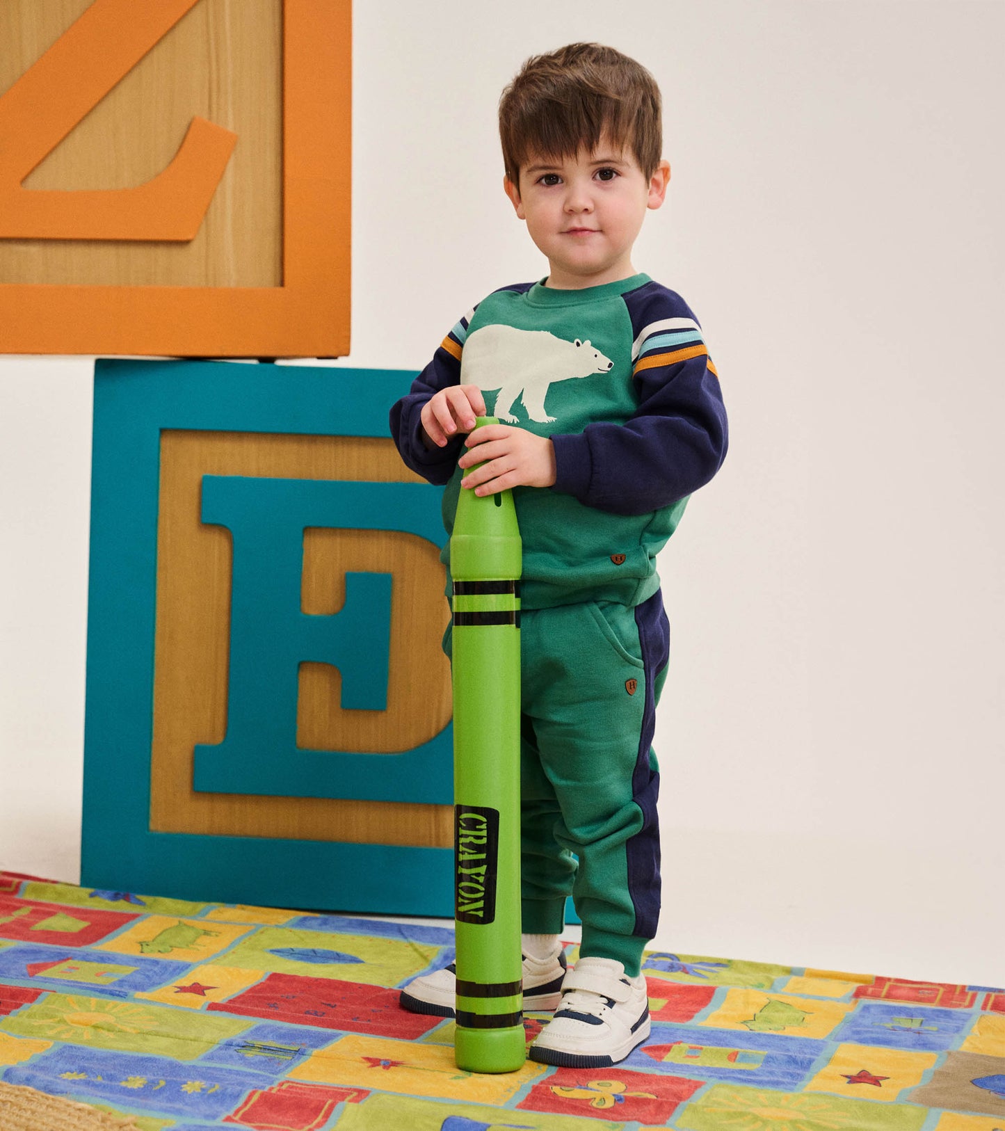 Toddler wearing green polar bear sweatshirt with navy sleeves and striped shoulders