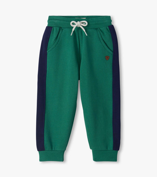 Bottle green track pants with navy side panels, white drawstring waist, side pockets, and cuffed ankles