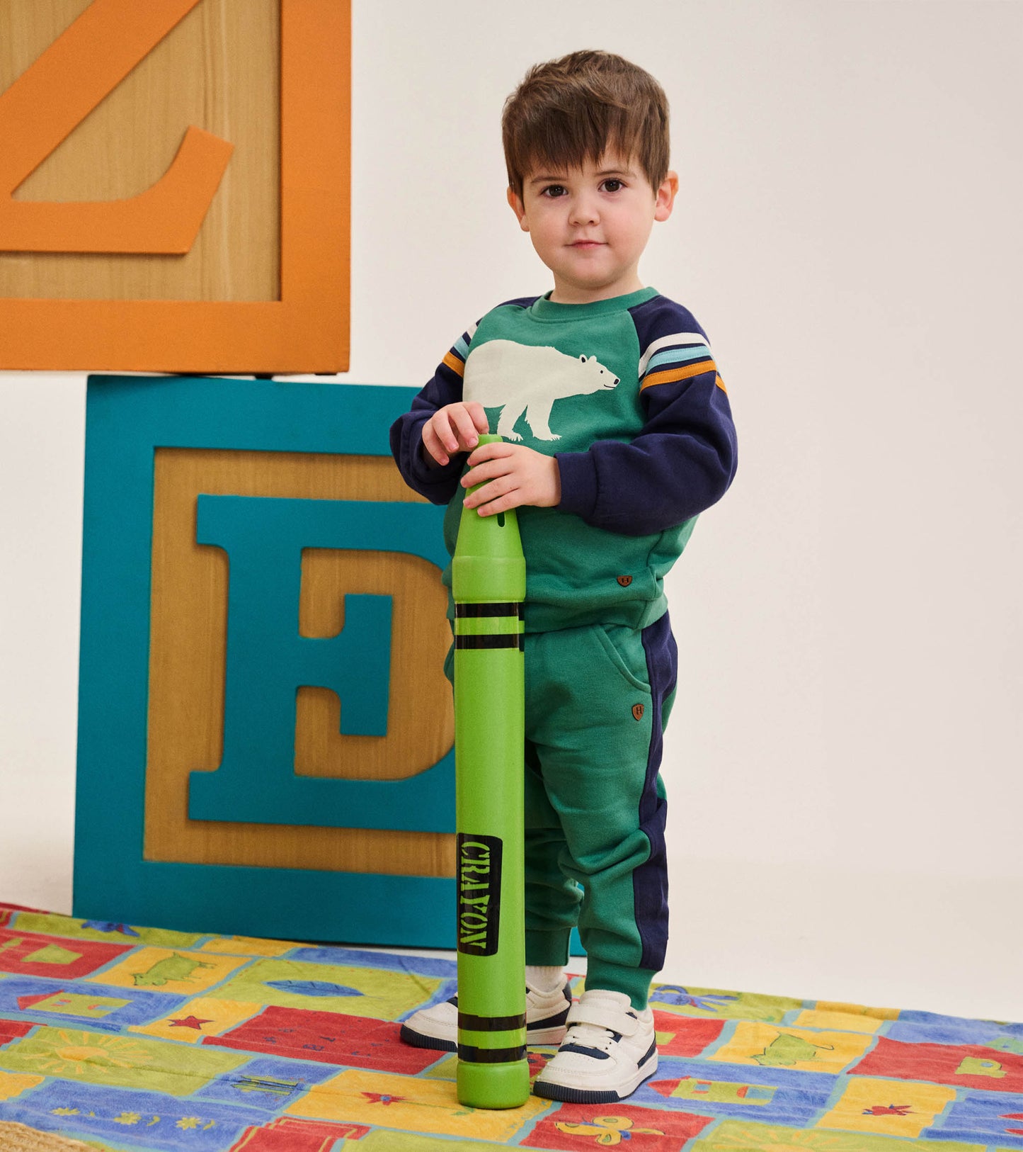 Toddler wearing bottle green track pants with navy side panels, shown with matching sweatshirt