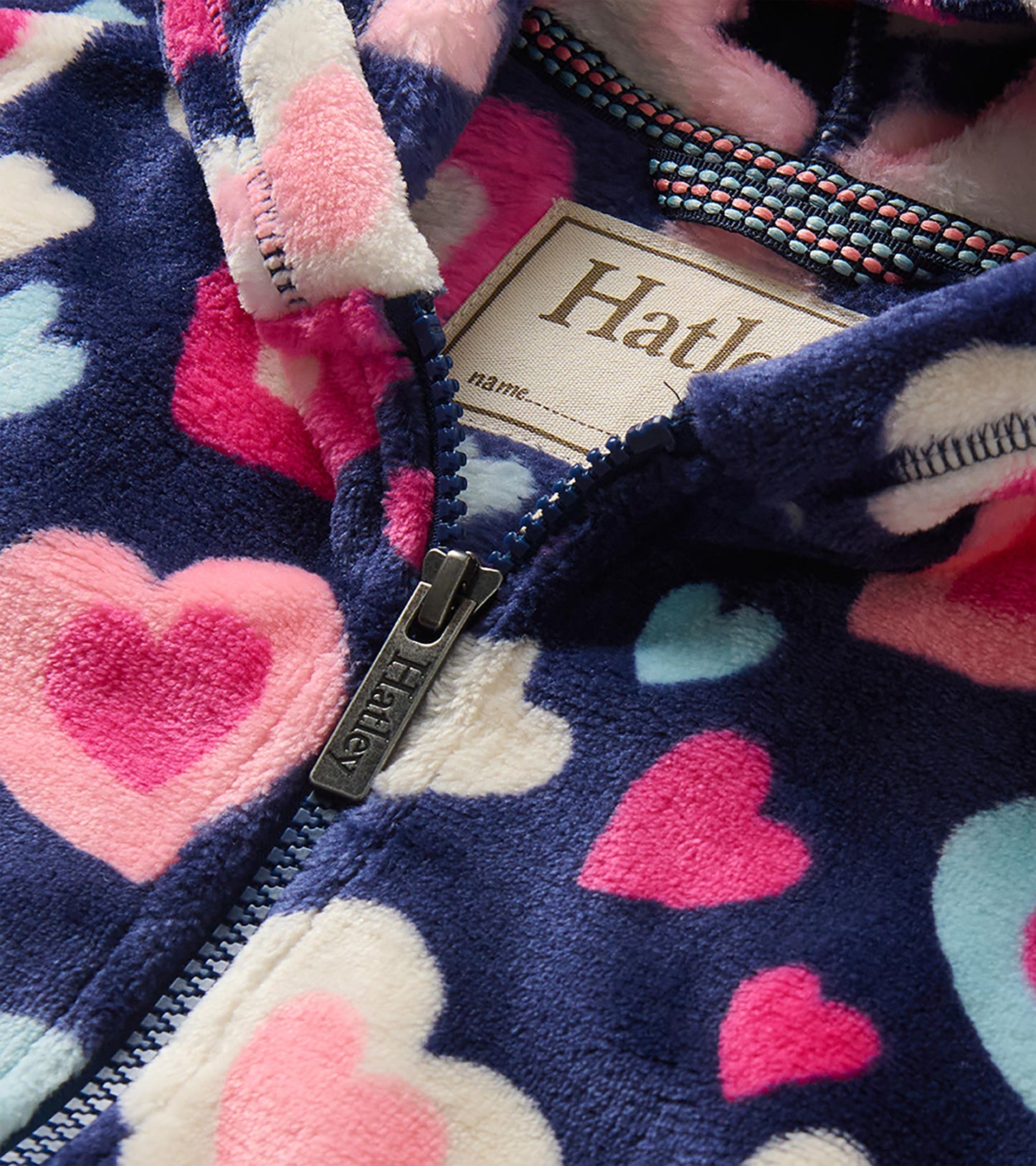 Close-up of navy heart-print hoodie with zipper, hood lining, and visible Hatley label