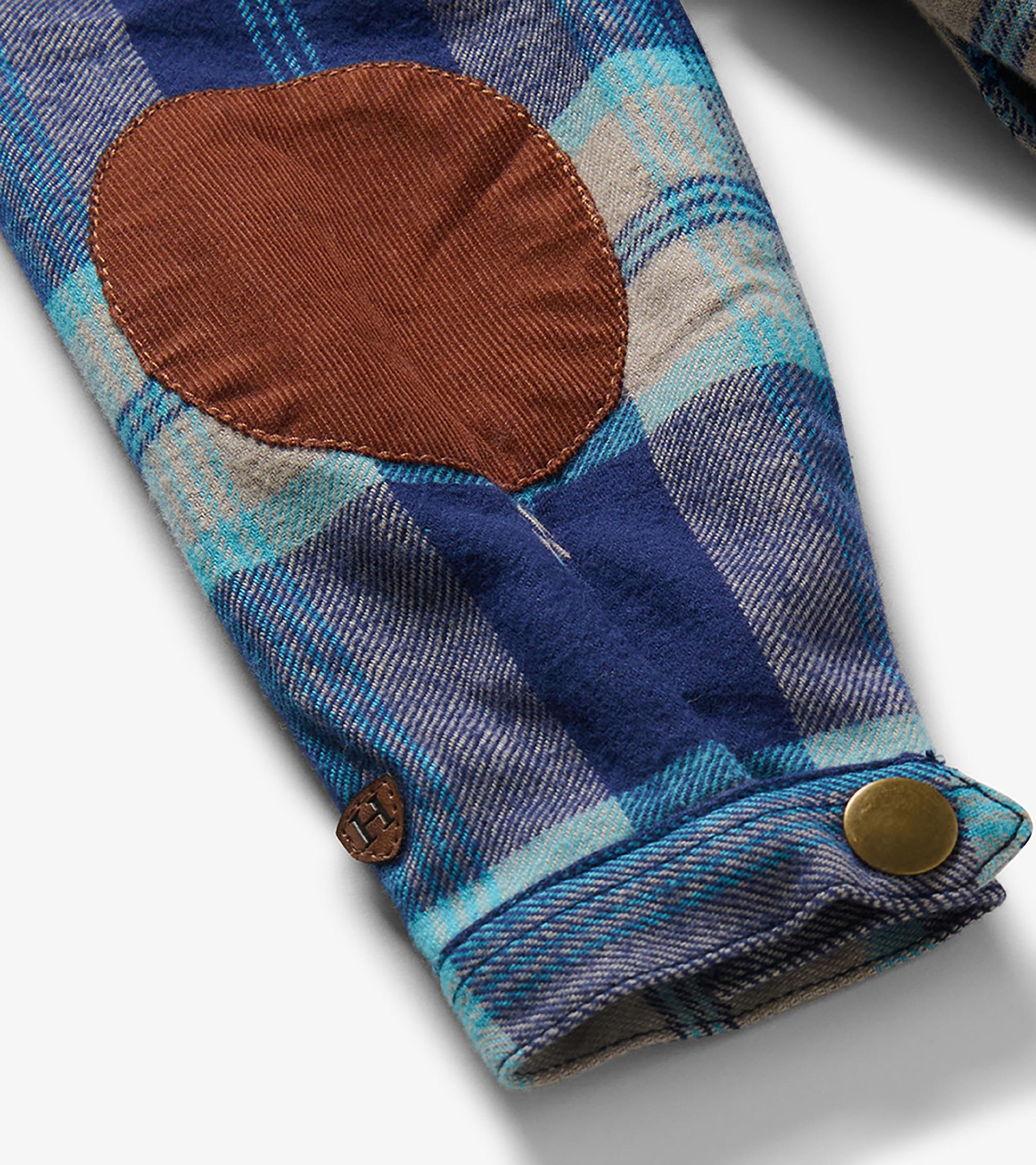 Close-up of sleeve on boys blue plaid hooded shirt jacket with brown elbow patch and snap cuff
