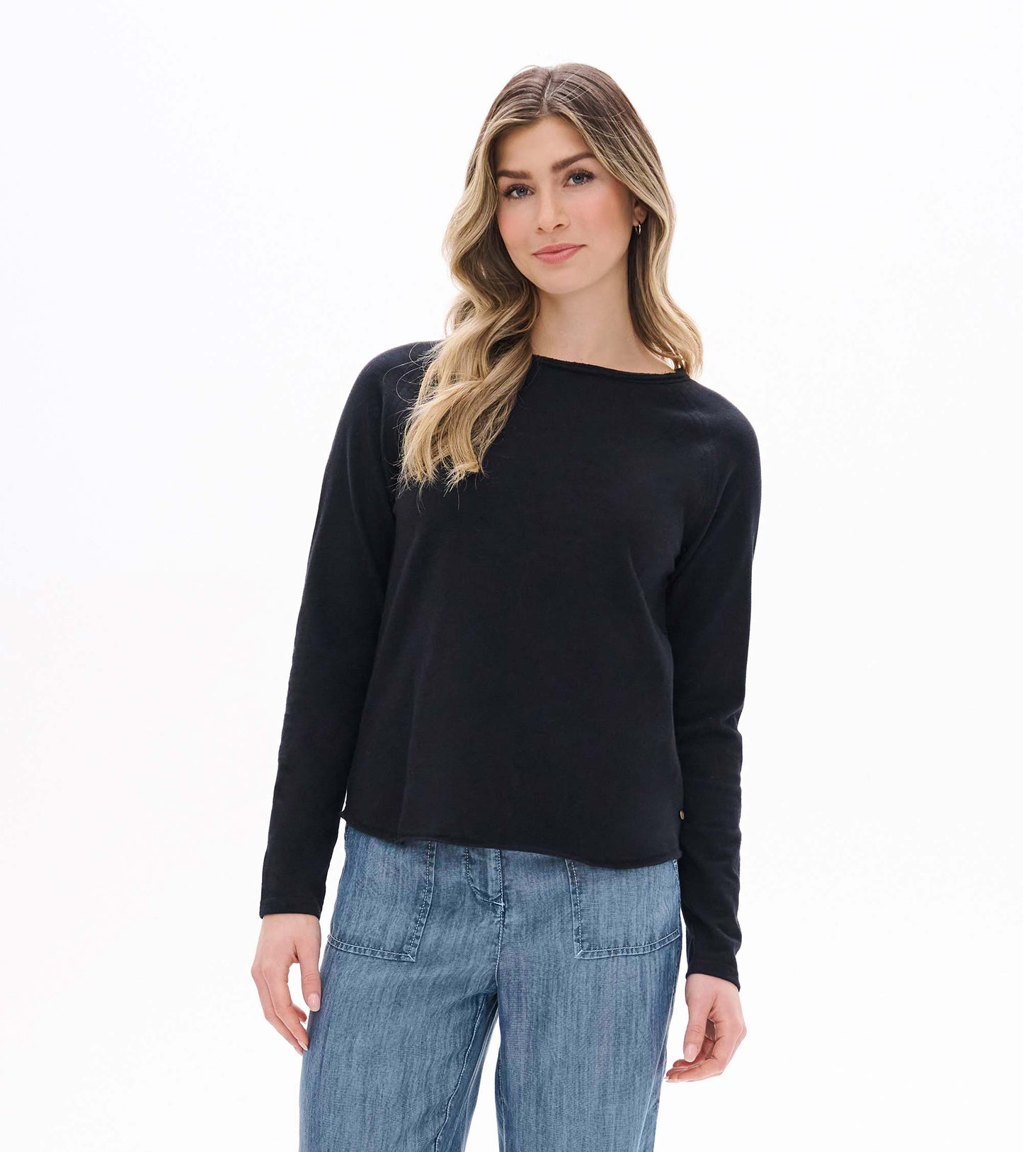Front view of black raglan sleeve tee with long sleeves and a curved hem on model