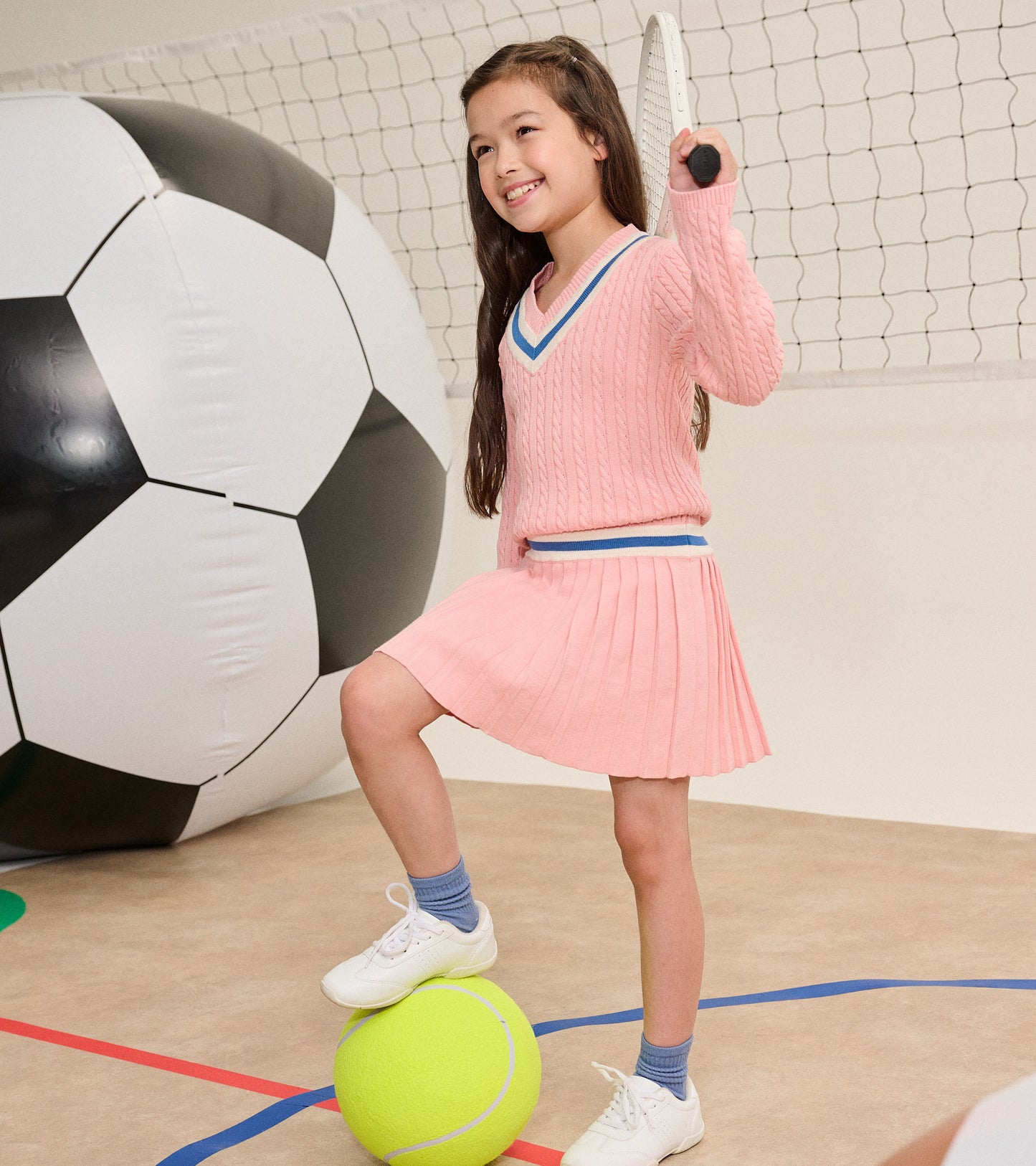 Girl modeling blossom pink cable-knit dress with pleated skirt and striped V-neck