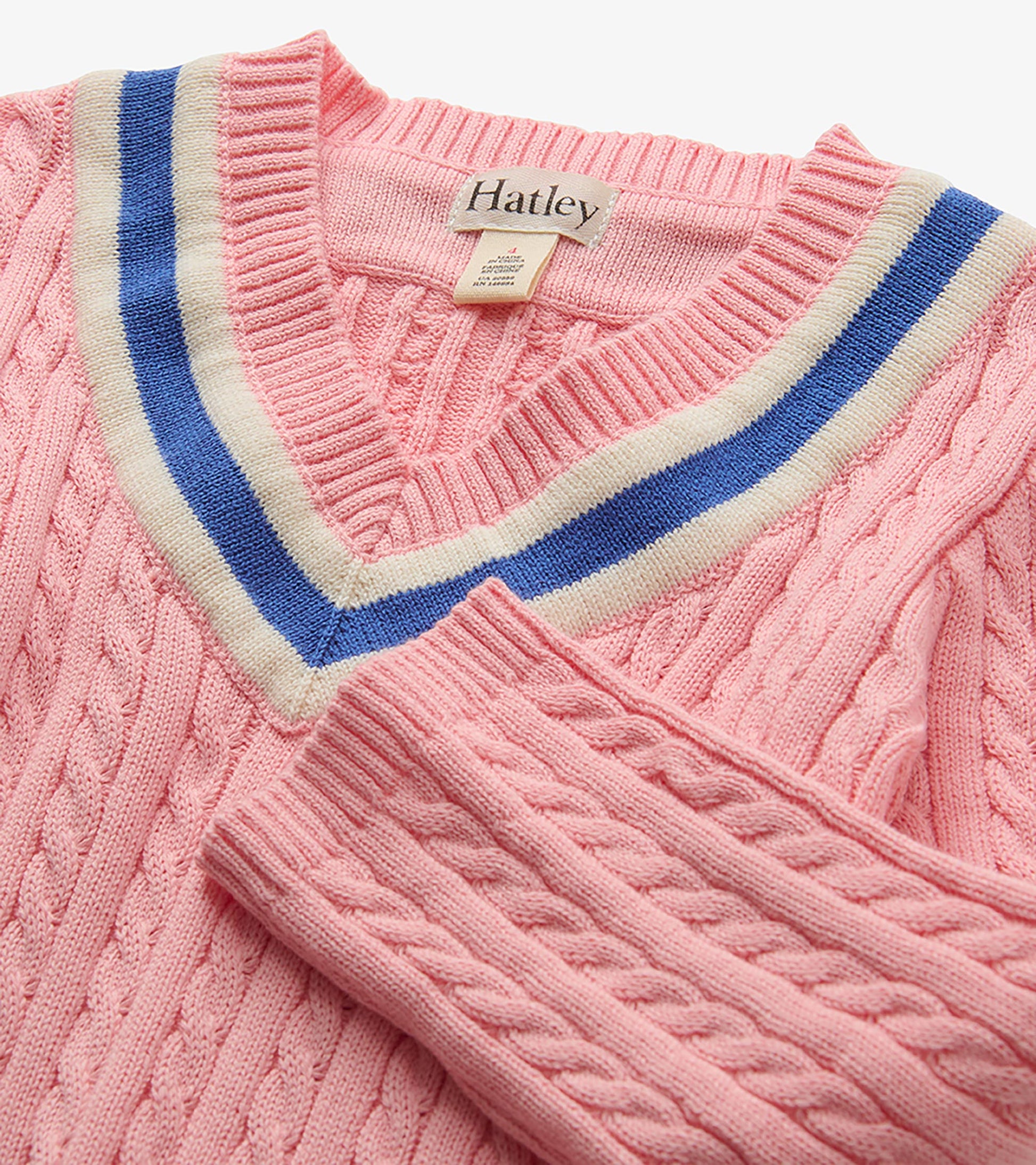 Close-up of pink cable-knit dress V-neck with blue and cream striped trim and Hatley label