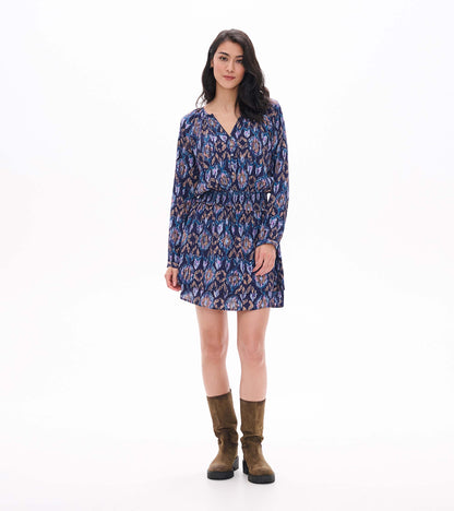 Front view of smocked waist mini dress with long sleeves, buttoned V-neck, and blue textured ikat print