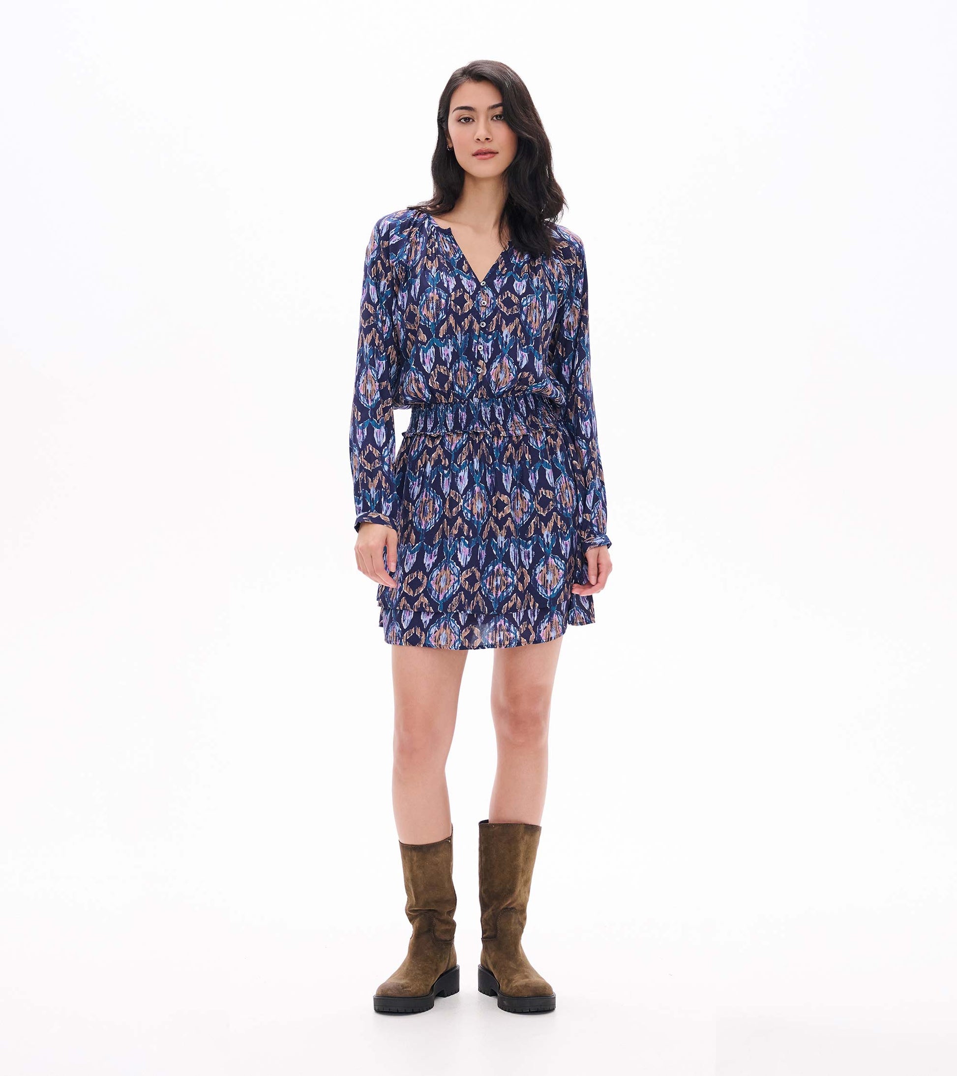 Full front view of blue textured ikat mini dress with long sleeves, smocked waist, and layered skirt