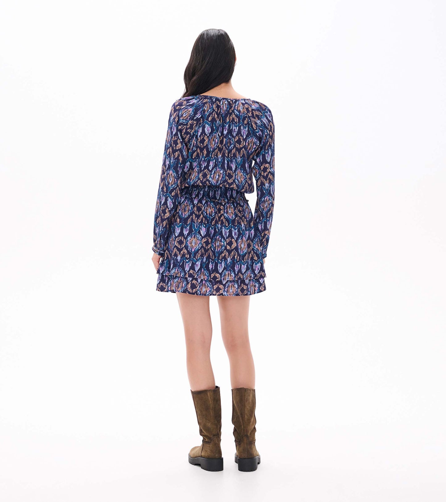 Back view of navy ikat print mini dress with long sleeves, smocked waist, and tiered ruffle skirt